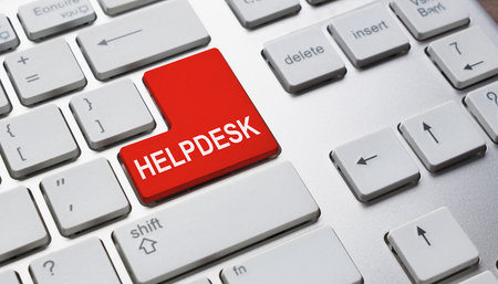 Close up of a red keyboard key with the word HELPDESK on a silver computer keyboardの素材