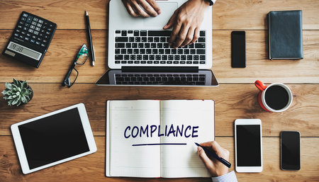 Hands typing on a laptop next to a notebook with COMPLIANCE written on it Clear details and vibrant colors en...の素材