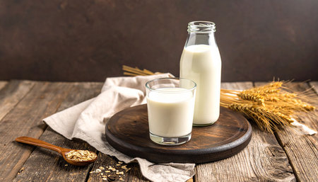 Oat milk in a bottle and glass on a wooden background.の素材