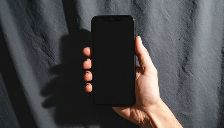 male hand holds the phone with a black screen on a dark backgroundの素材