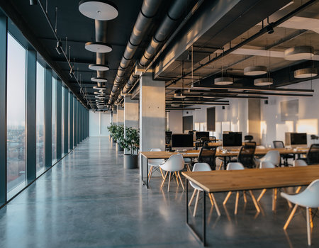 Interior of modern coworking office with glass walls, concrete floor and rows of computer tables with chairs. 3d renderingの素材