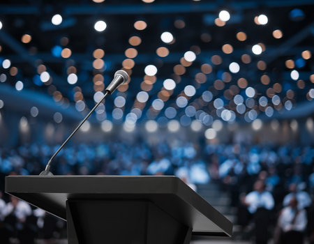 Podium with microphone and crowd of people in conference hall or seminar hallの素材