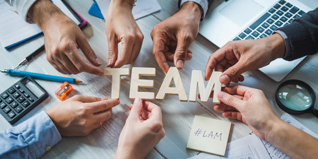Teamwork concept. Top view of business people assembling wooden cube with word team.の素材