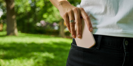 Woman using smart phone in the park. Close-up of female hands holding mobile phone.の素材