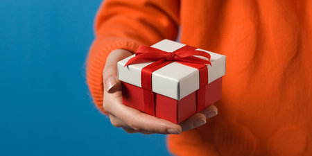 Woman holding gift box on blue background, closeup. Christmas presentの素材