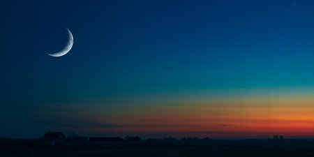 Beautiful sunset over the village with a crescent moon in the foregroundの素材
