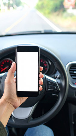 Mockup image of a hand holding mobile phone with blank screen while driving a carの素材
