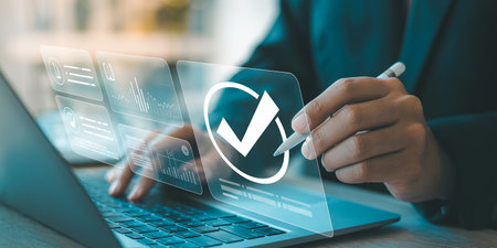 Businessman using laptop computer with check mark icon on virtual screen.の素材