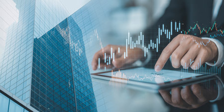 Close up of businessman using digital tablet with double exposure of financial graph.の素材