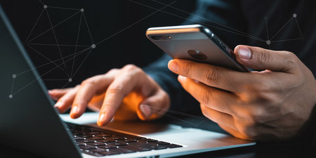 Man using mobile phone and laptop computer. Close up of male hands using smartphone.の素材