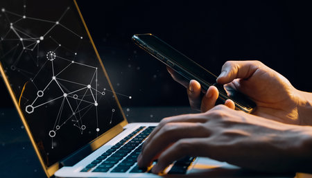 Close up of hands using mobile phone and laptop with network connection conceptの素材