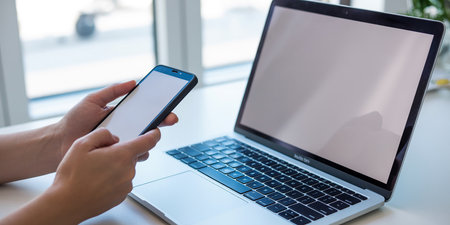 Cropped image of businesswoman using mobile phone and laptop in officeの素材