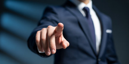 A man in a dark suit points his index finger forward against a blurred background.の素材