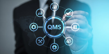 Businessman touches QMS digital interface with icons for quality control and business processes.の素材