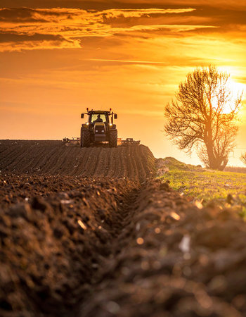 Tractor preparing land with seedbed cultivator at spring sunset.の素材