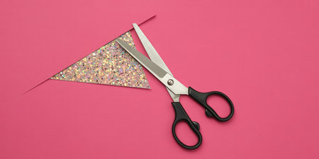 Scissors cutting colorful paper on a pink background. Top view.の素材