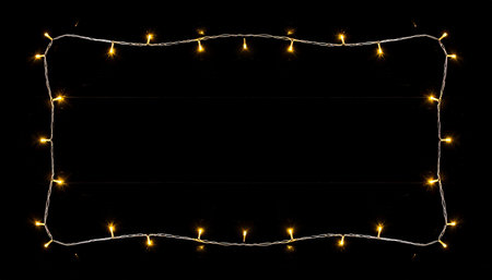Christmas lights on a black background. Glowing garland. Place for text.の素材