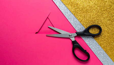 Scissors cutting red and gold paper with copy space for text.の素材
