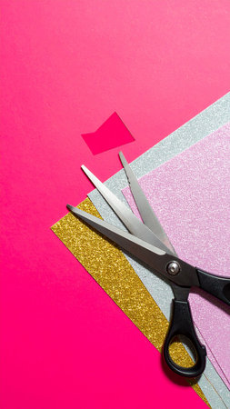Scissors cutting pink and golden paper on pink background with copy spaceの素材