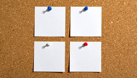 Three white paper notes pinned to a cork board with red pinsの素材