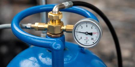 Pressure gauge on blue gas cylinder, close-up view.の素材