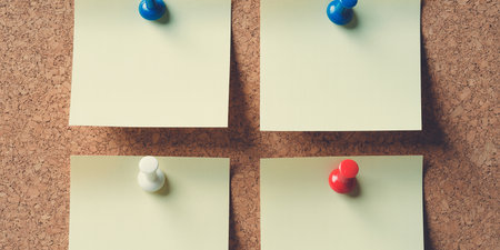 Three sticky notes pinned to a cork board with red and green pinsの素材
