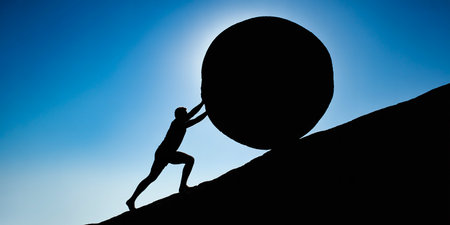 Silhouette of a man pushing a huge ball on a rockの素材