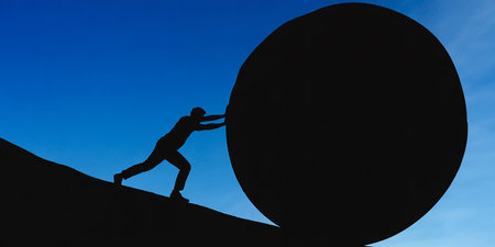 Silhouette of a businessman pushing a huge ball in the skyの素材