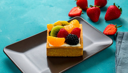 Piece of cake with fresh fruit on blue background, selective focus.の素材