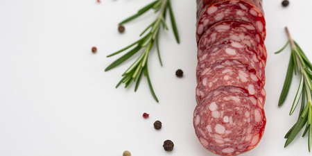 Salami with rosemary and peppercorns on a white backgroundの素材