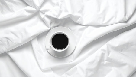 Cup of coffee on white bedding with copy space. Top viewの素材