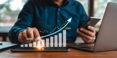 businessman using smart phone and laptop computer and graph business growth on wooden deskの素材