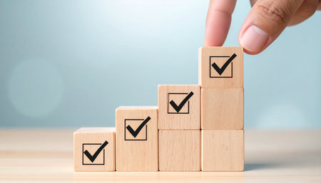 Hand of business woman putting wooden cube block with check mark icon on top of wooden block stacking as step stair to success in business concept.の素材