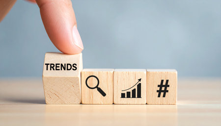 Concept of business success, growth and progress. Businessman's hand turns wooden cubes and changes the word Trends to Trends.の素材