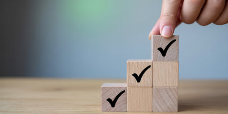 Businessman hand arranging wooden cube block stacking as step stair with check mark icon on topの素材