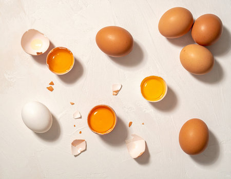Eggs and broken eggshells on white background, top viewの素材