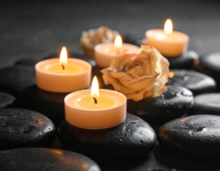 Spa stones with burning candles and flowers on black background, closeupの素材