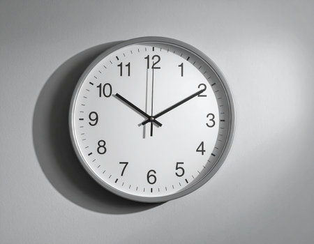 White wall clock showing five minutes to twelve o'clock on gray backgroundの素材