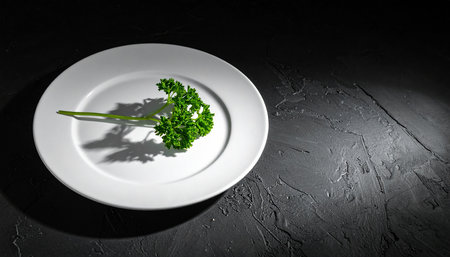 Fresh parsley on a white plate on a black background, top viewの素材