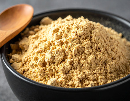 Organic ginger powder in black bowl with wooden spoon on black background.の素材