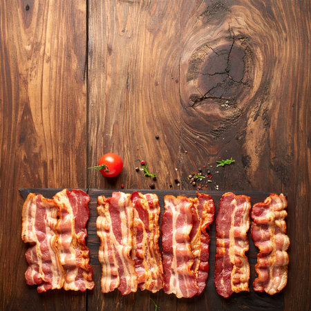 Slices of bacon on a wooden background. Top view.の素材