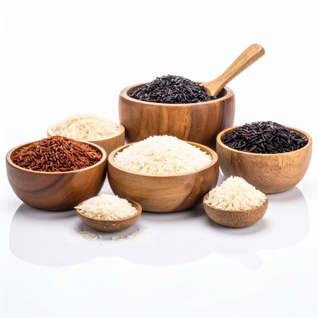 Different types of rice in wooden bowls and spoons on white backgroundの素材