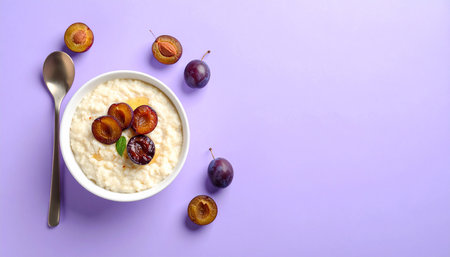 Oatmeal porridge with plums and spoon on violet background, top viewの素材