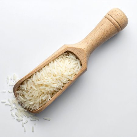 Rice in a wooden scoop on white background. Top view.の素材