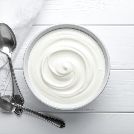 Greek yogurt in a bowl on a white wooden background. Top view.の素材