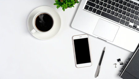 White office desk table with laptop, smartphone and coffee cup. Top view with copy space, flat lay.の素材