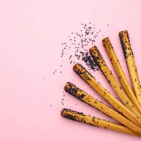 Bread sticks with poppy seeds on pink background, top view.の素材