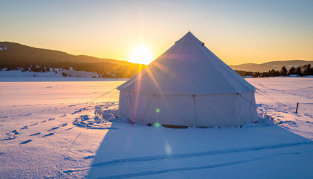 White canvas yurt in a snow-covered field during a sunset with sun flare. Clear details and vibrant colors en...の素材