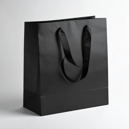 A black paper shopping bag with black ribbon handles is shown against a clean white background.の素材