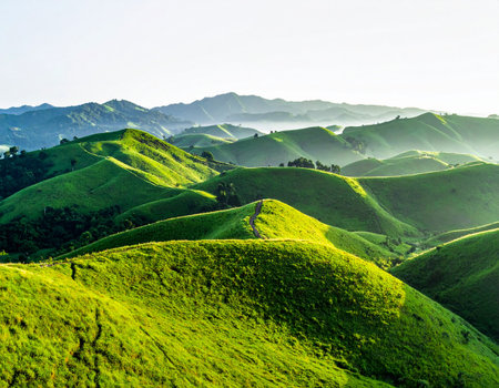 Rolling green hills under a bright sky with a winding path leading through the landscape.の素材